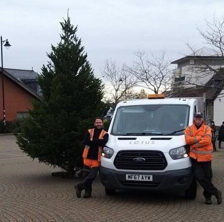 Xmas tree by two man and a vehicle.